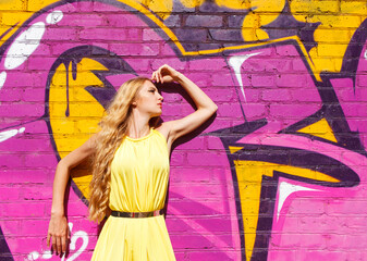 Young attractive blond girl near the wall with graffiti