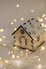 Wooden toy house with garland lights on a white background