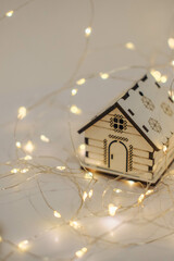 Wooden toy house with garland lights on a white background