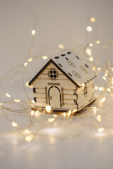 Wooden toy house with garland lights on a white background