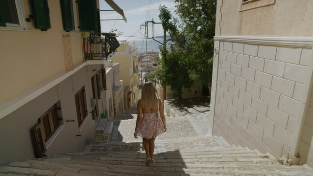 A young woman walking the steps of a small greek island. Syros, greece.