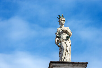 Fototapeta na wymiar Marble Statue of Justice. Goddess of justice holding law scales and a sword (Themis). Freedom square (Piazza della Liberta), Udine, Friuli-Venezia Giulia, Italy, Europe.