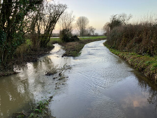 Flood water on lane from overflowing stream after heavy rain during Storm Henk, East Chinnock,...