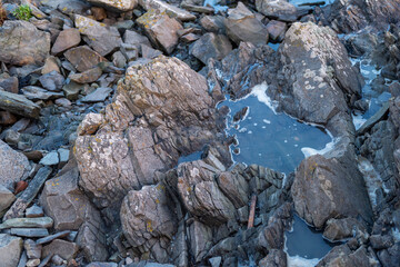 imagen detalle textura suelo rocoso, con distintas grietas y profundidades y algún pequeño charco de agua 
