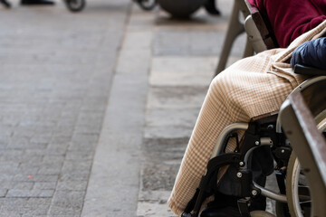 Obraz premium Unrecognizable elderly man in a wheelchair on the street with a blanket on a winter day