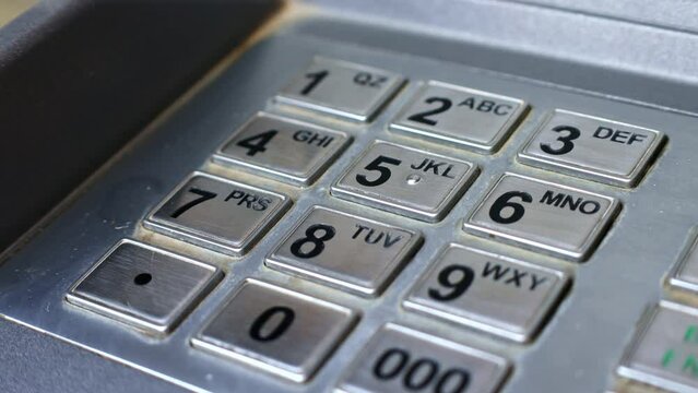 Woman hand entering pin code on the keypad of ATM banking machine for cash withdrawal close up