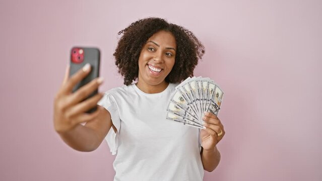 African american woman with braids taking selfie with money against pink background