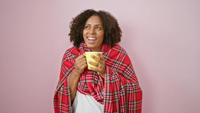 African american woman with braids wearing a plaid shawl, holding a yellow mug against a pink background