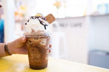 A woman's hand holds a blended coffee mug with delicious toppings