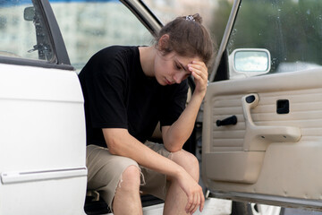 a young male driver feel sad and depressed in the white old car