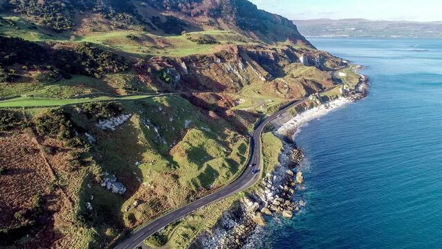 Northern Ireland, UK, Atlantic coast with cliffs. Causeway Coastal Route with car and parking.. One of the most scenic coastal roads in Europe. Aerial 4K video. Winter, sunrise light