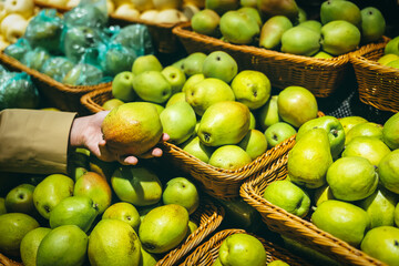 Young Asian woman shopping in supermarket, picking fresh organic vegetables and fruits