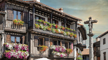 Cruz de piedra del siglo XVIII y hermosa arquitectura tradicional con balcones adornados con...