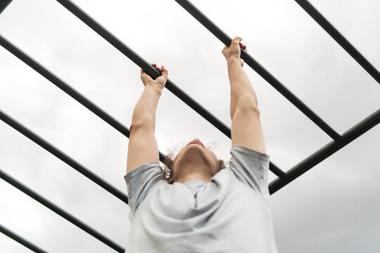 fitness workout on monkey bars outdoors, arm muscles training, climbing on ladder