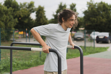A Determined Athlete doing power workout in the park, push ups on the metal bars