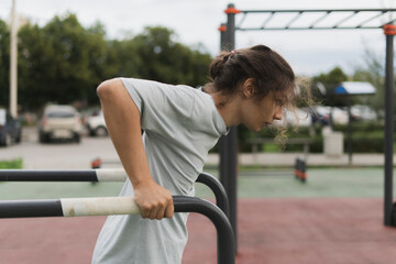 A Determined Athlete doing power workout in the park, push ups on the metal bars
