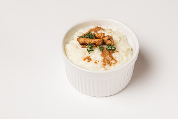 Isolated creamy rice pudding sprinkled in the cinnamon powder and top with walnuts and thyme in a white form on a white background