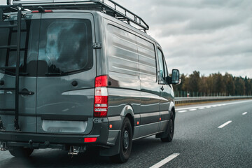 Camper van on the public road. Offroad modern van for traveling with a ladder on the back and an...