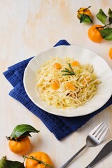 Cabbage salad with tangerines in a ceramic plate on a light concrete background. Salad recipes. Healthy food