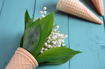 Poster bouquet of white lily of the valley flowers in a waffle cone on close up © Viktoriia Kolosova