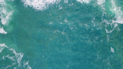 Rough blue ocean splashing foaming on stone cliff aerial view. Coastal scenery.