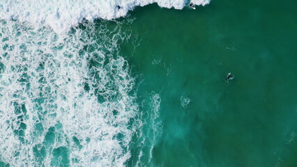 Aerial view surfboarders waiting ocean waves lying on surfboard. Tropical beach