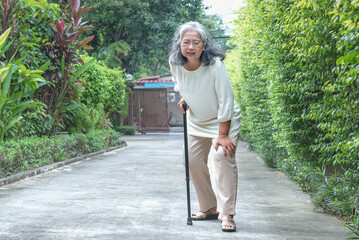Elderly woman walking on the road She has knee pain due to osteoporosis. Retirement age and the concept of health care.