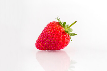 Fresh organic strawberries on a white reflective surface. Close up shot.