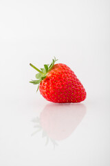 Fresh organic strawberries on a white reflective surface. Close up shot.
