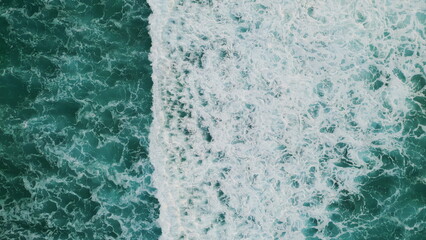 Turquoise water washing seashore aerial view. Marine landscape with foamy waves.