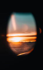 Sunset out of airplane window over Asia, warm sunset over clouds in plane. 
