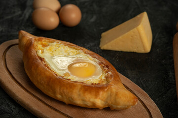 . Caucasian flatbread adjarian khachapuri with egg on a dark wooden . Adjarian Khachapuri Georgian cheese bread