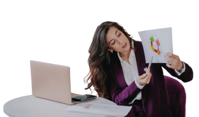 Brunette businesswoman in dark violet suit and white shirt sitting at table with laptop, pointing by pen on diagram of business strategy via video call against transparent background.