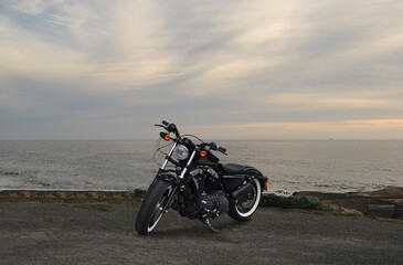 Fototapeta na wymiar Black classic vintage style bike stopped with sunset, seascape behind