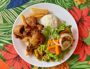Savory Delight: Well-Prepared Fried Chicken, Rice, and Vegetables on a Floral Tablecloth.