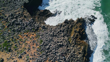 Aerial view foamy coast washing by stormy ocean. Rough sea waves crashing stone