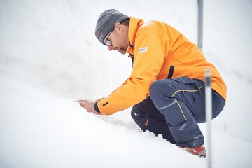 engineer analyzing snowpack stability on a steep slope