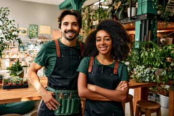 Family business of gardeners. A man and a woman in professional clothes are standing in their own plant shop and smiling.