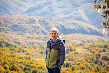 Fototapeta premium Adult man standing on the background of autumn mountains