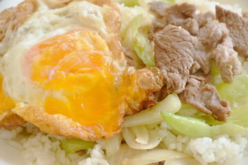 spicy stir fried slice beef meat with long sweet chili and onion on rice topping egg in plate 