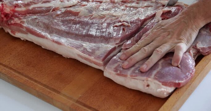 Pork preparation for oven roasting, arranging piece of pork belly using knife, close-up