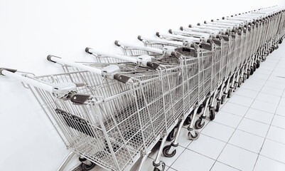 Grocery carts in a row against a white wall. Parking of grocery carts. Black and white. Monochrome...