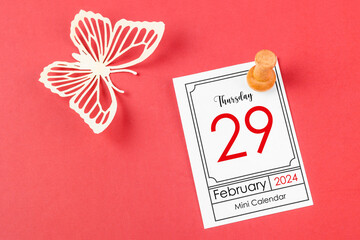 February 29th mini calendar for February 29 and wooden push pin on red background.