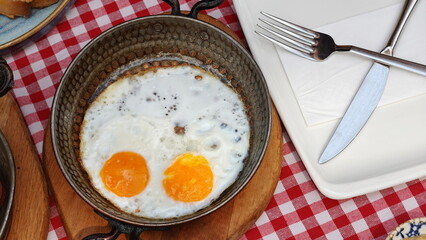 Fried eggs in a frying pan On a red checkered tablecloth