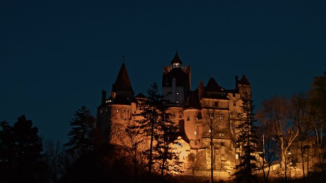 Establishing aerial shot of medieval Bran Dracula Castle in Transylvania. Spooky Halloween castle shrouded in mist and illuminated by the light of the full moon at night