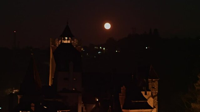 Establishing aerial shot of medieval Bran Dracula Castle in Transylvania. Spooky Halloween castle shrouded in mist and illuminated by the light of the full moon at night