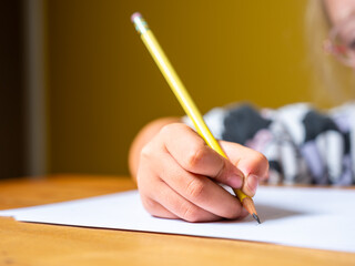 Close-up shot of girl children holding yellow pencils. Children holding yellow pencils and trying to write.
