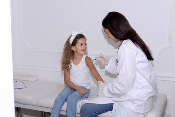Doctor holds an injection vaccination child , 5-6 year old girl at the doctor's office
