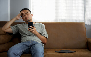 Young man sitting on sofa at home talking on phone and smiling