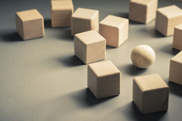 Closeup a wooden sphere in a group of wood cubes, business in high competition, be different in...